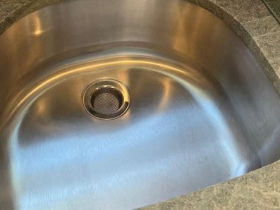 After: the same basin with the brushed finish restored and the strainer clear.