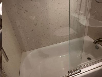 After: the same screen cleared so the tub and tiling behind the glass read sharply.