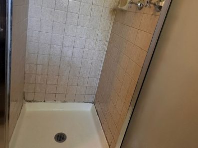 After: the same shower pan cleaned to a white surface with the grout lines lifted.