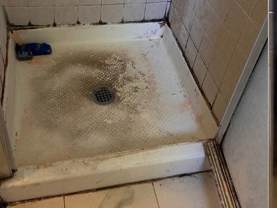 Before: a shower pan with dark soil across the floor and staining along the tile grout.