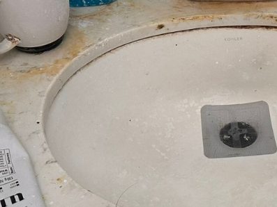 Before: a bathroom vanity with rust staining around the tap base and residue across the basin.