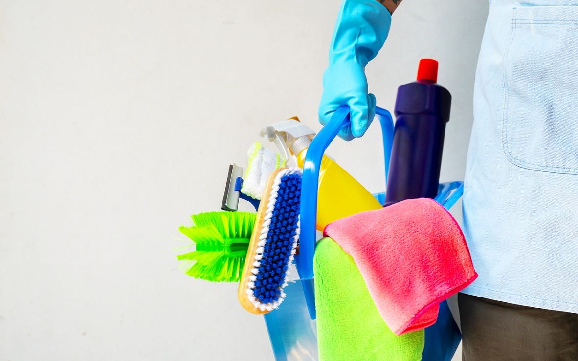 Cleaner carrying a caddy loaded with scrub brushes, cloths and spray bottles