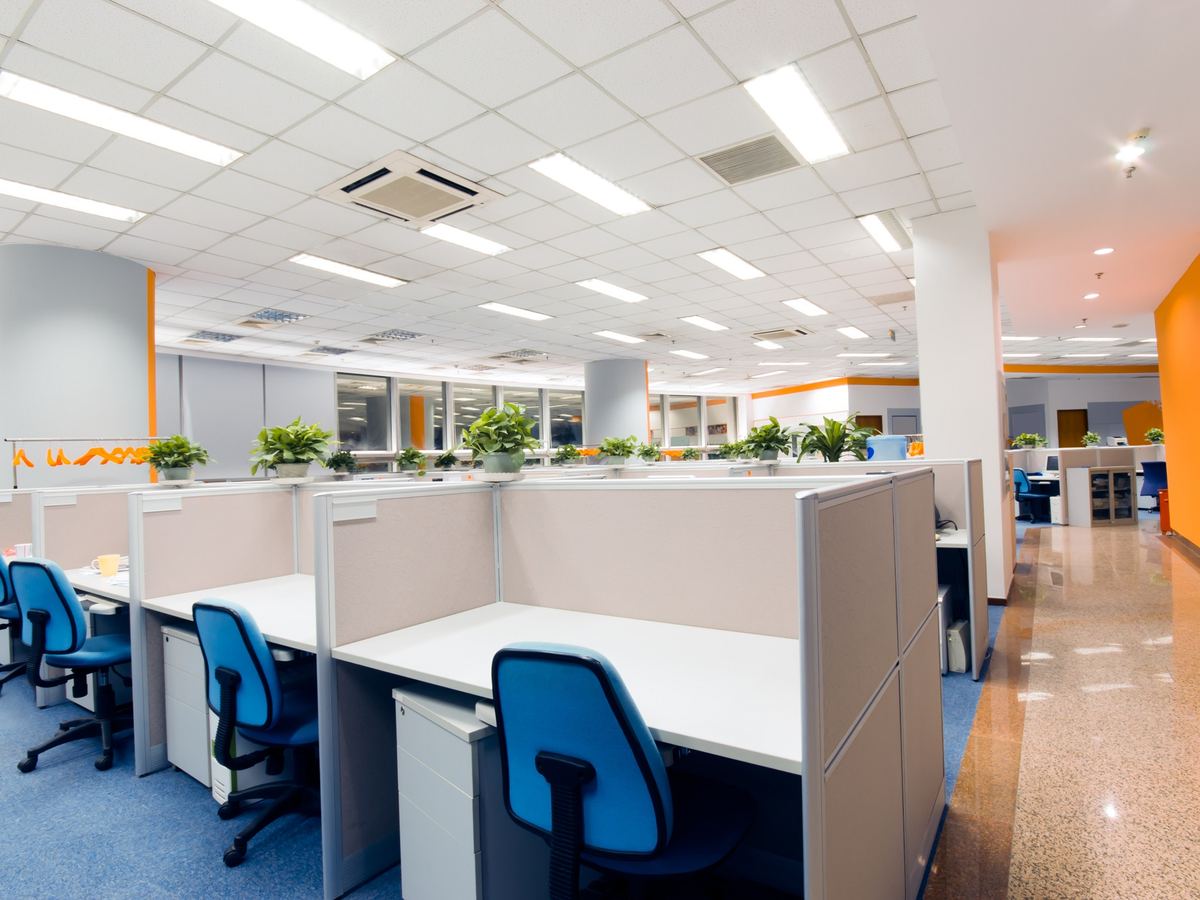 Open-plan office with rows of desks, chairs and a polished corridor floor