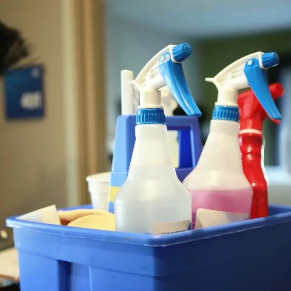 Caddy of spray bottles and cloths set down inside a guest room