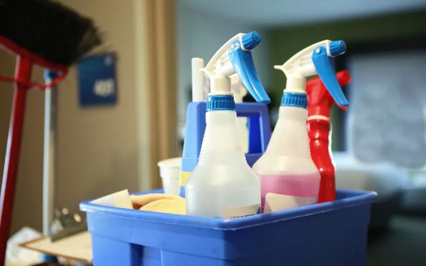 Caddy of spray bottles and cloths set down inside a guest room