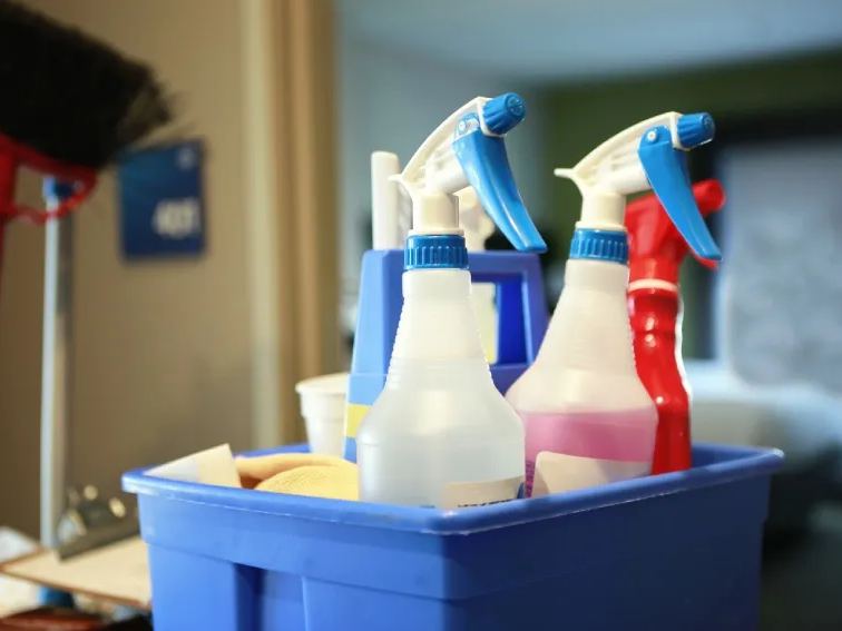Caddy of spray bottles and cloths set down inside a guest room